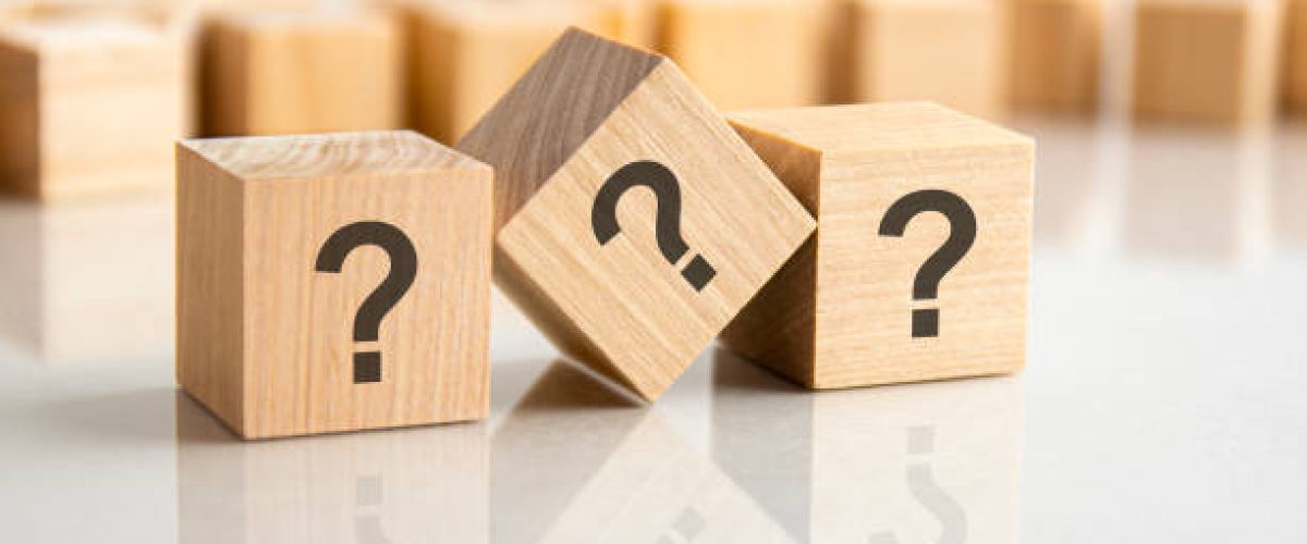 three question marks written on wooden cubes lying on the gray table, business and education concept. close-up cubes